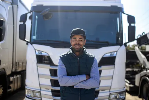 Smiling truck driver standing in front of his cab