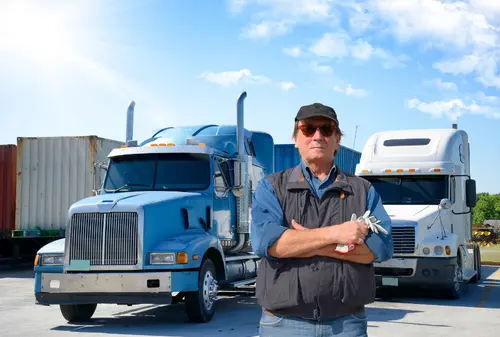 Trucker stands in front of blue container truck and white cab